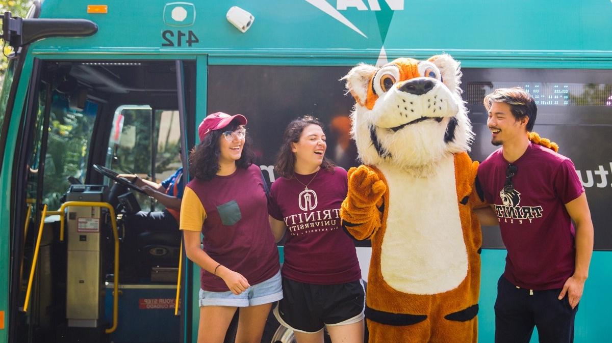 three students and the LeeRoy mascot stand in front of the VIVA culture bus